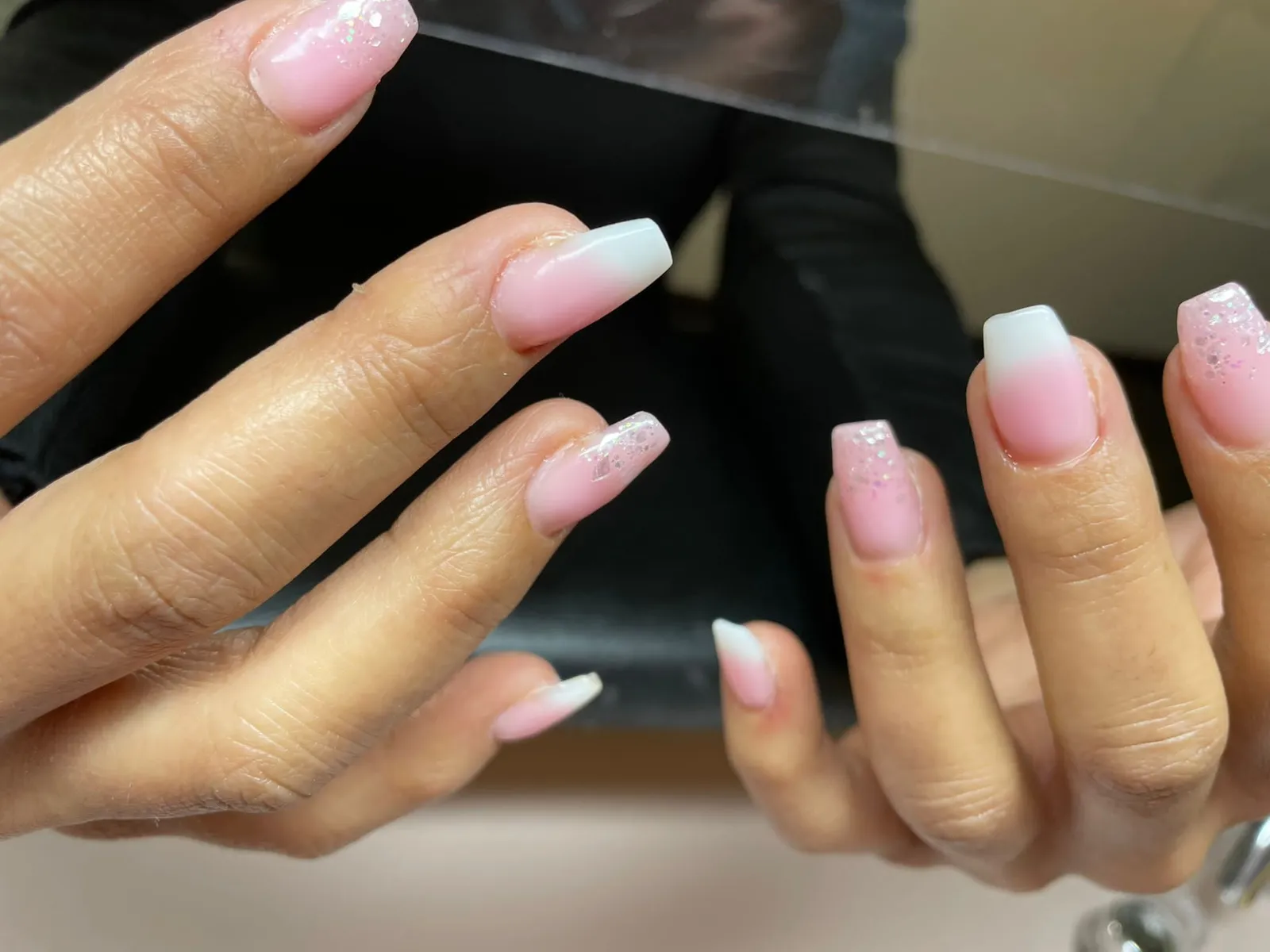 Hand mit frisch modellierten Gelnägeln in zartem Rosa mit Glitzer.