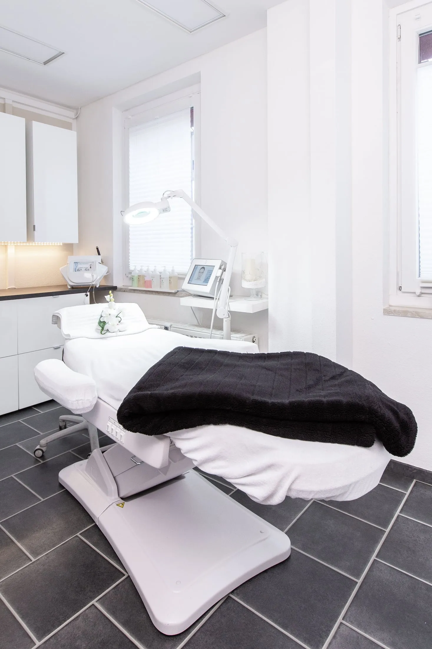Behandlungsstuhl mit dunkler Decke und Lupenleuchte im Behandlungsraum.