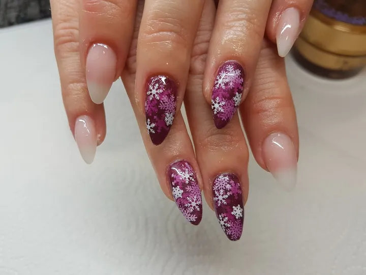 Spitze Gelnägel in Nude, zwei Nägel mit Schneeflocken auf Beerenrot.