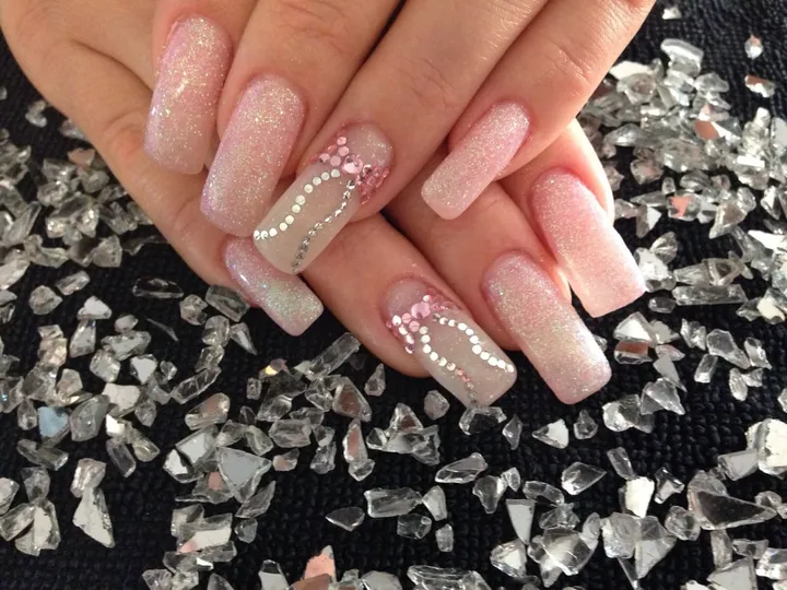 Rosé Gelnägel mit kleinen Glitzerpunkten auf Glassplittern.