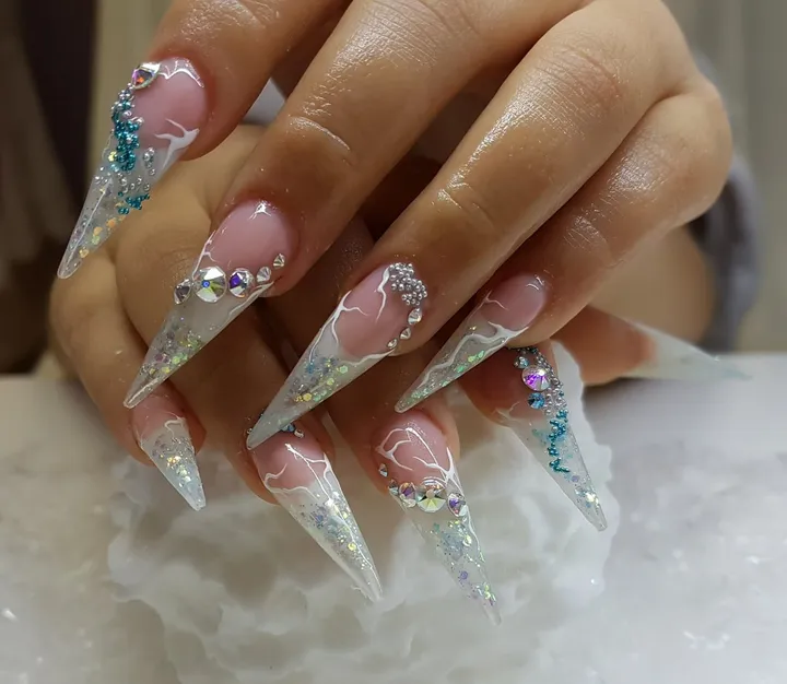 Lange spitze Nägel, durchsichtig mit Glitzer und Steinchen.