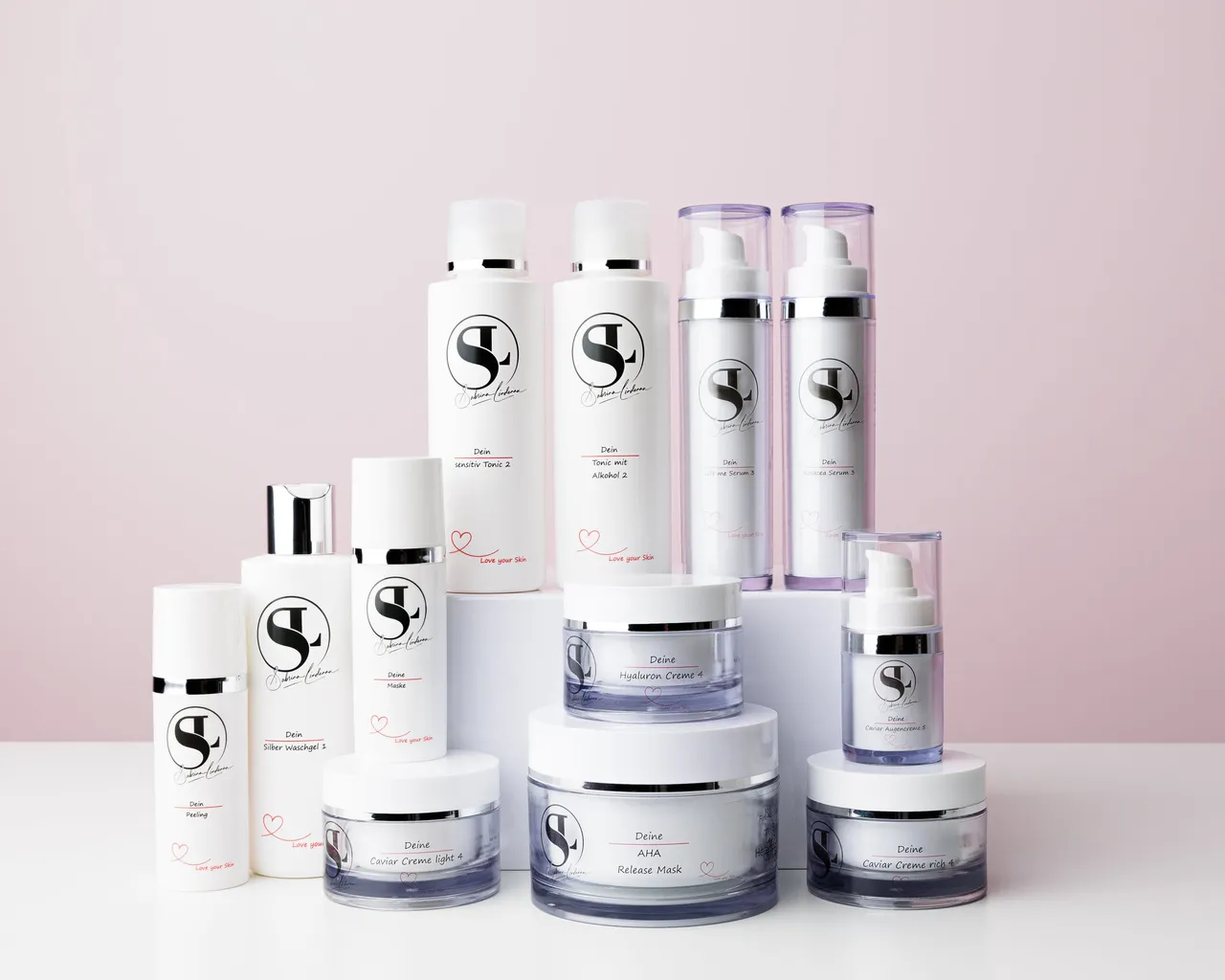 Flaschen, Spender und Tiegel von SL-Cosmetic vor rosa Hintergrund.